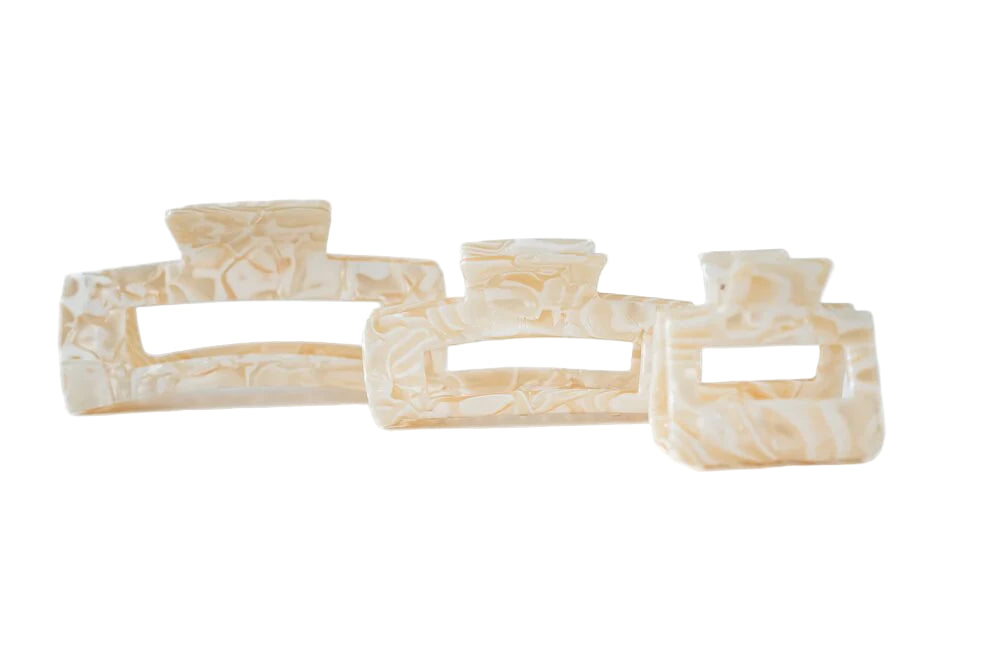 Three beige hair clips stacked on a white background